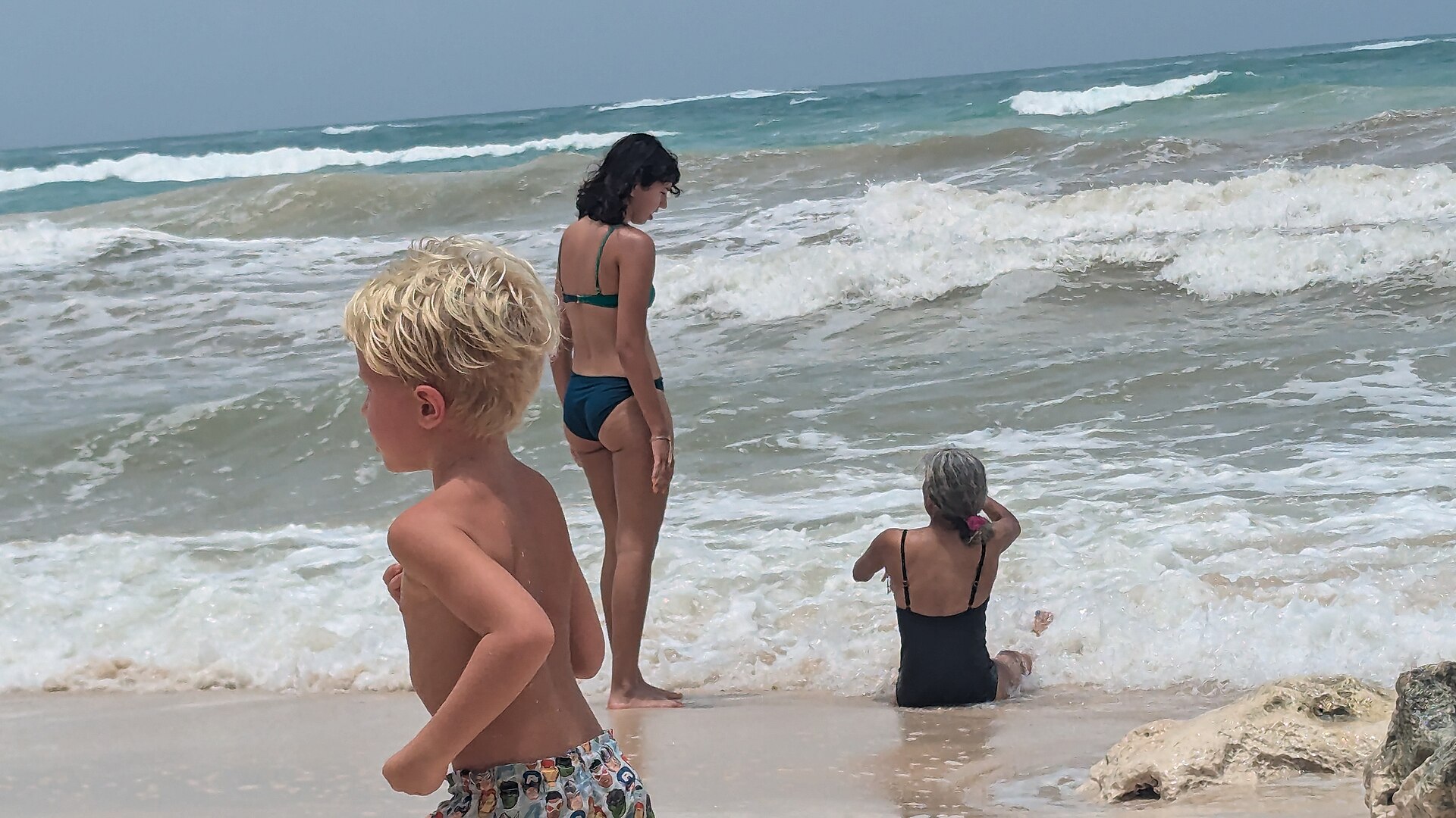A child playing on the sand along Tulum's beach road